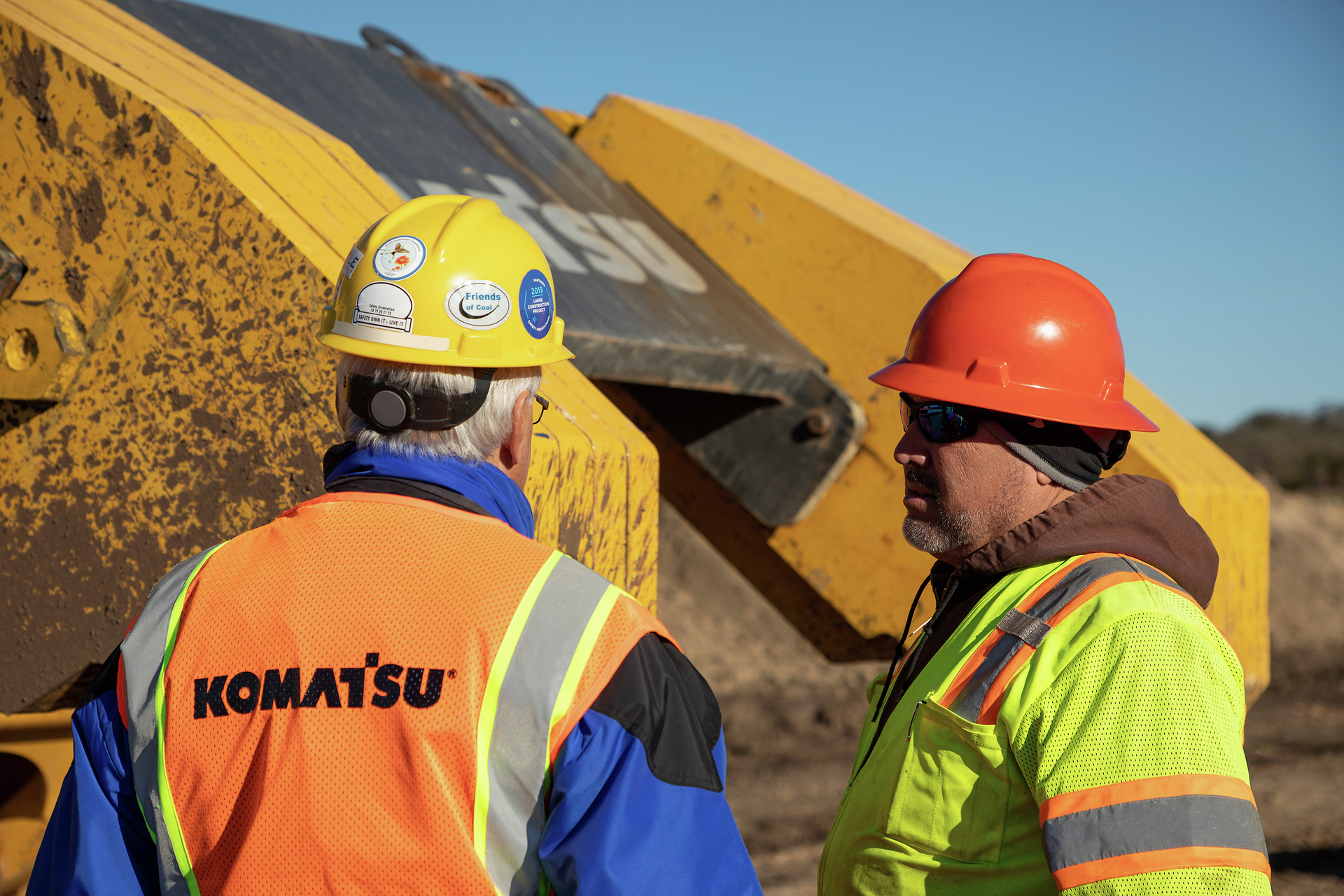 Men talking in front of Komatsu equipment