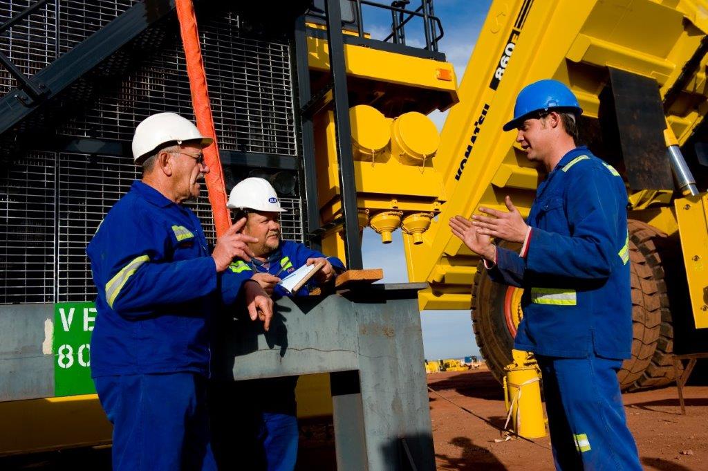 a komatsu technician repairing an excavator at a customer work site.