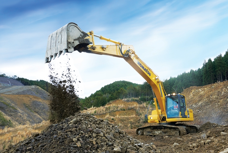 Komatsu excavator moving soil in open terrain.