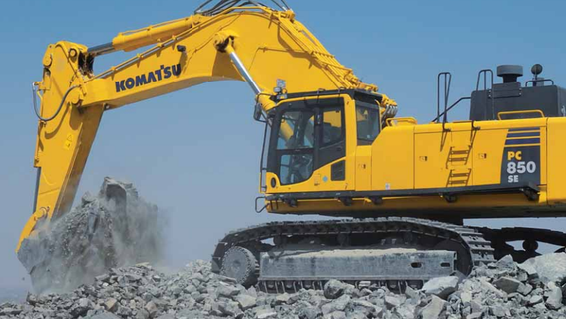 Komatsu PC850 excavator moving rocks on a work site.